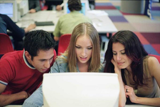 Tres estudiantes atentos à pantalla de una computadora.