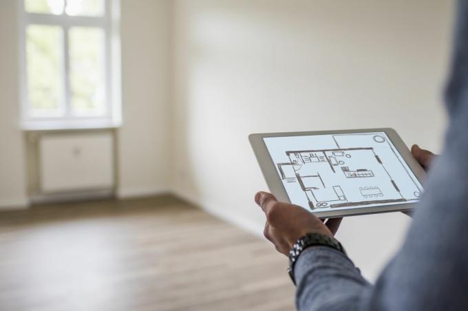 Homem na nova casa segurando o tablet exibindo uma planta digital