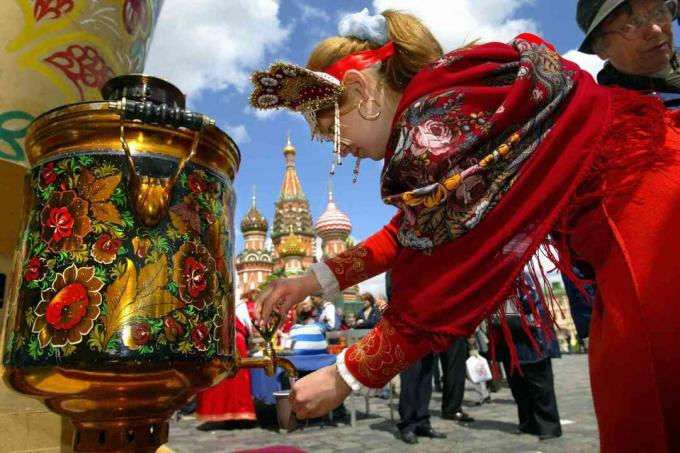 Garota russa vestindo uma roupa tradicional derrama água do samovar