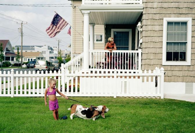 Niña com perro delante de sua casa. Bandera americana ondeando