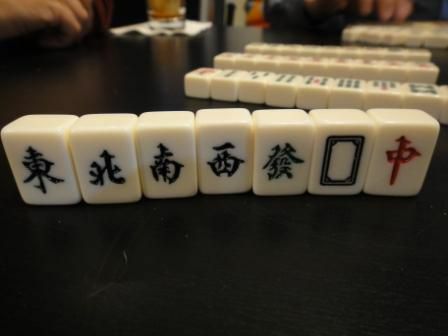 Os ladrilhos de ventos e dragões em um Mahjong colocam-se em pé sobre uma mesa.