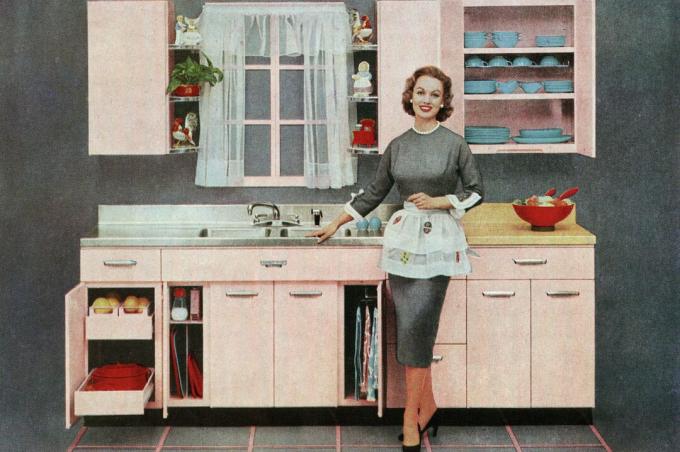 Ilustração vintage de uma dona de casa elegante em pé na frente de sua nova cozinha rosa, 1957
