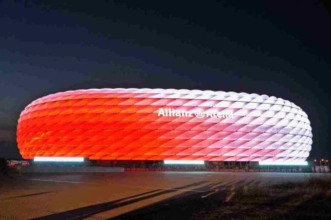 branco de dia, o exterior esculpido da Allianz Arena brilha em vermelho à noite