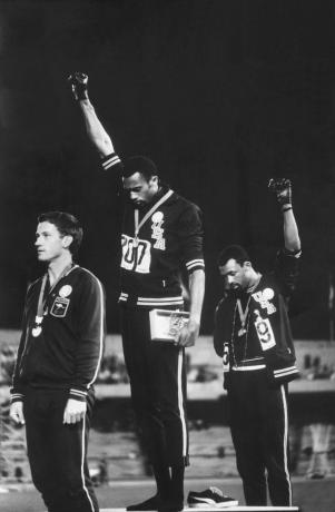 Fotografia dos membros afro-americanos da equipe de atletismo Tommie Smith e John Carlos levantando os punhos enluvados do Black Power como protesto pelos direitos civis durante cerimônia de medalha nos Jogos Olímpicos de 1968 na Cidade do México