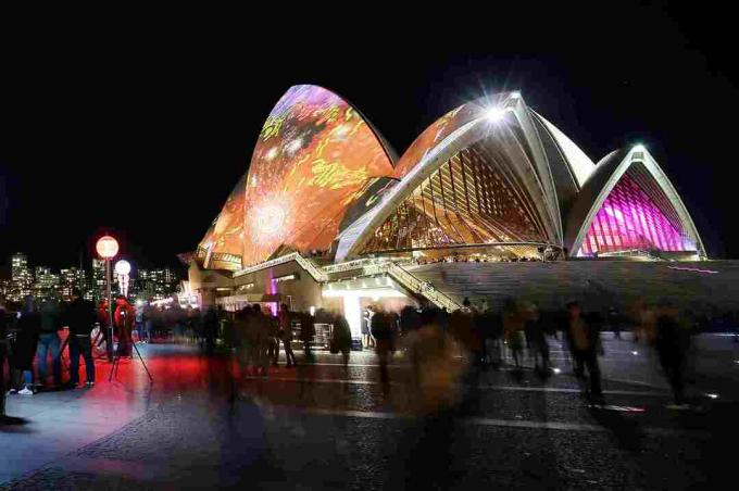 visão noturna do edifício em forma de concha colorida iluminada perto de um corpo de água