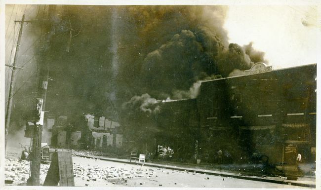 Propriedades danificadas e fumaça provenientes de edifícios após o Massacre de Tulsa Race, Tulsa, Oklahoma, junho de 1921.