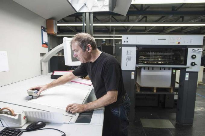 Trabalhador preparando equipamento de impressão digital em oficina de impressão
