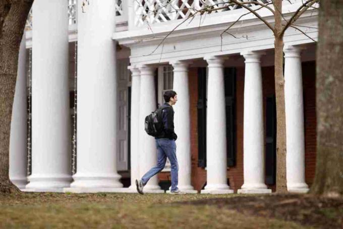 estudante andando em um campus da faculdade perto de colunas da Toscana