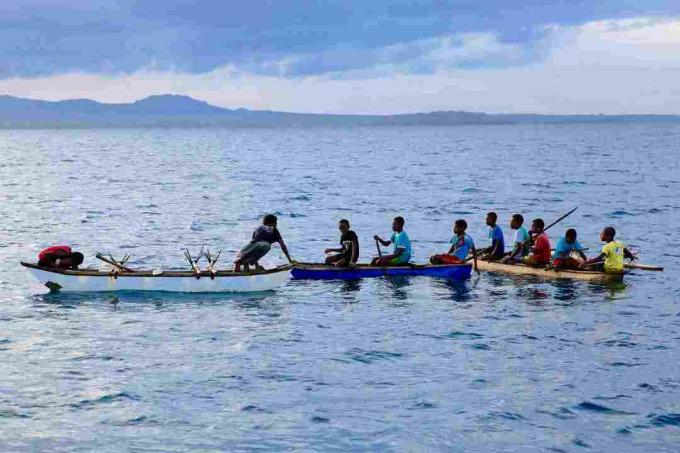 Rapazes em canoas no noroeste de Malakula, Vanuatu.