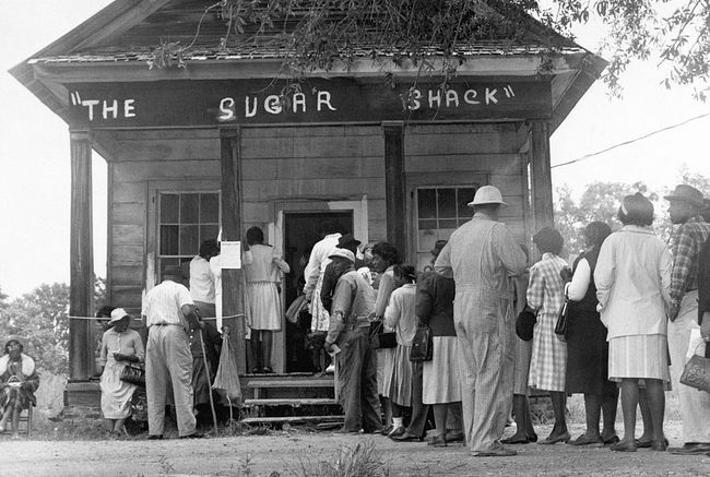 Eleitores afro-americanos, capazes de votar pela primeira vez na zona rural do condado de Wilcox, no Alabama, fazem fila em frente a um posto de votação após a aprovação da lei federal de direitos de voto em 1965.