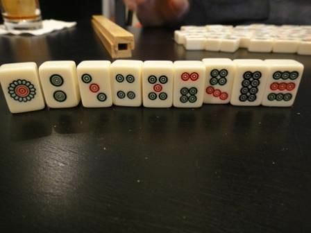 O traje de pedras de um conjunto padrão de peças de Mahjong em pé sobre uma mesa.