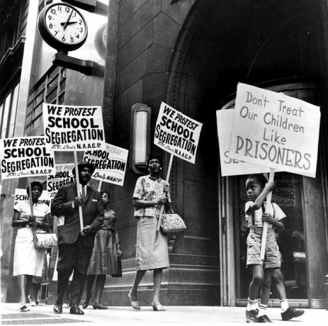 Manifestantes, um menino entre eles, fazem piquete em frente à secretaria de uma escola em protesto contra a segregação.