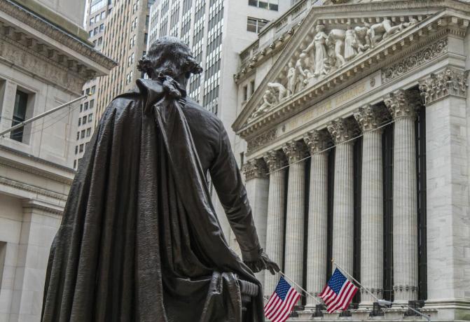 Uma estátua de George Washington olha para o prédio da Bolsa de Nova York na Broad Street do Federal Hall National Memorial em Wall Street na cidade de Nova York.