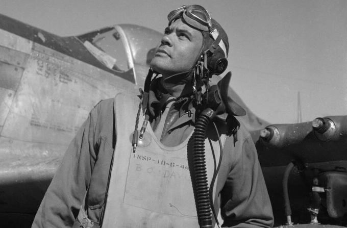 Benjamin O. Davis em um traje de voo e capacete em pé na frente de um caça P-51 Mustang.