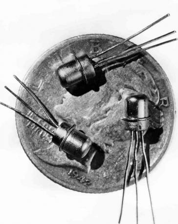 Imagem datada de 1956 de três transistores M-1 em miniatura vistos na face de uma moeda de dez centavos