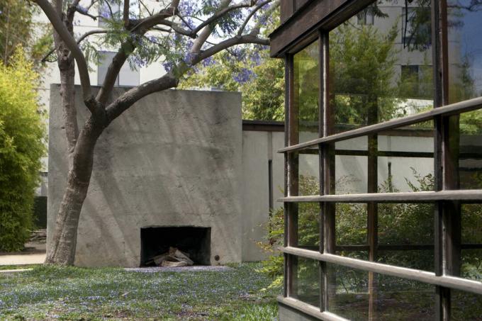 Uma lareira externa em uma parede de concreto em frente a uma parede de janelas