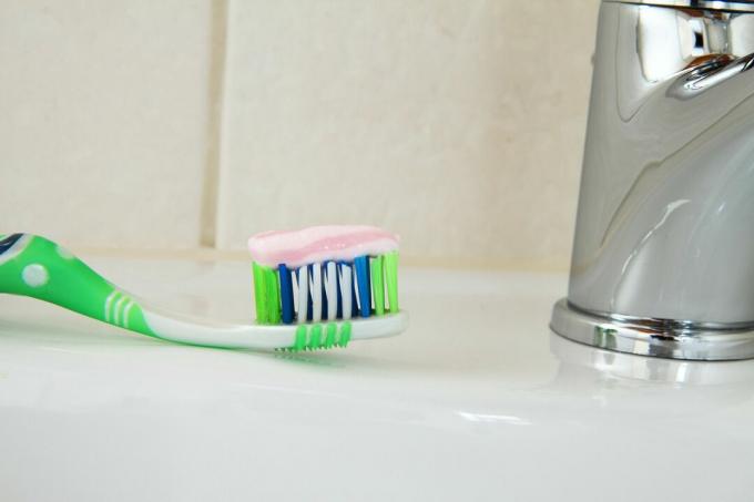 Perto de uma escova de dentes com pasta de dentes, sentado na pia.