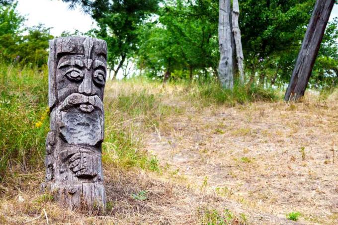 Ídolo de madeira do deus eslavo Perun por um caminho para uma floresta ucraniana.