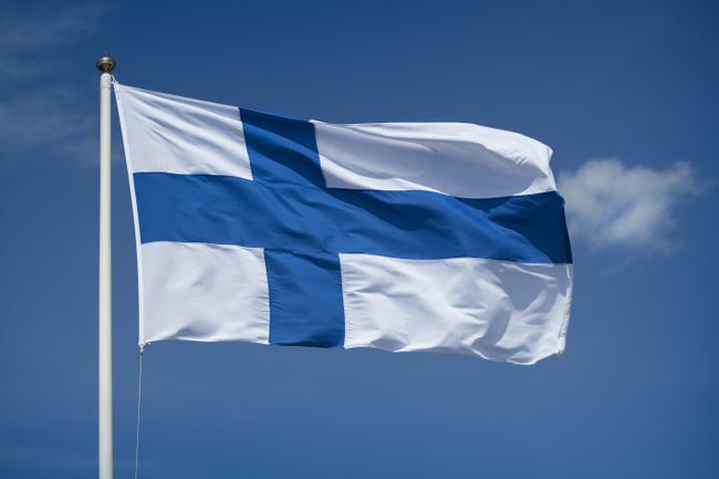 Bandeira finlandesa içada com fundo de céu azul