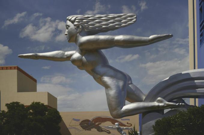 escultura de prata de mulher nua aparentemente correndo, cabelos esvoaçando atrás, um braço para frente e um braço atrás