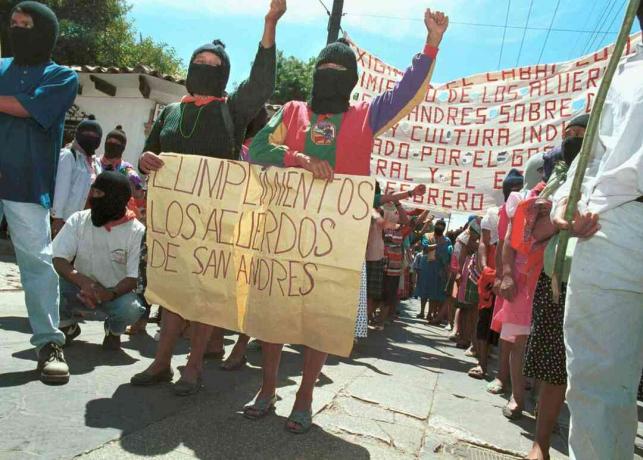 Duas mulheres seguram uma placa pedindo ao governo que cumpra os Acordos de San Andrés