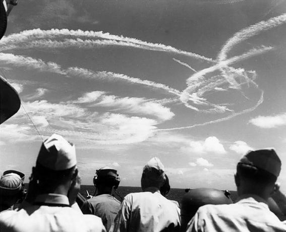 Marinheiros americanos olhando para o céu para os esteiras formadas por aeronaves lutando pela frota.