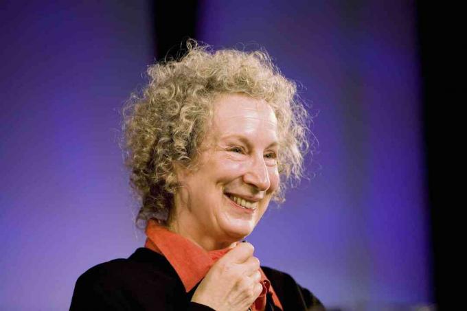 Imagem de Margaret Atwood sorrindo contra um fundo roxo