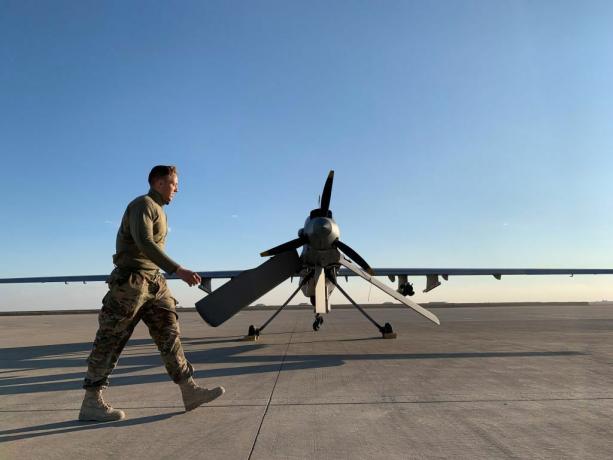 Um membro das forças americanas passando por um drone na base aérea de Ain al-Asad